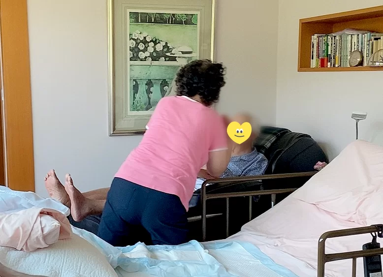가족 보호자가 침대에서 어르신을 돌보는 가족요양 장면