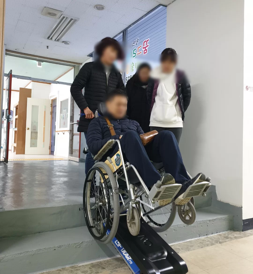 복지용구 지원으로 휠체어 경사로를 이용하는 어르신 모습