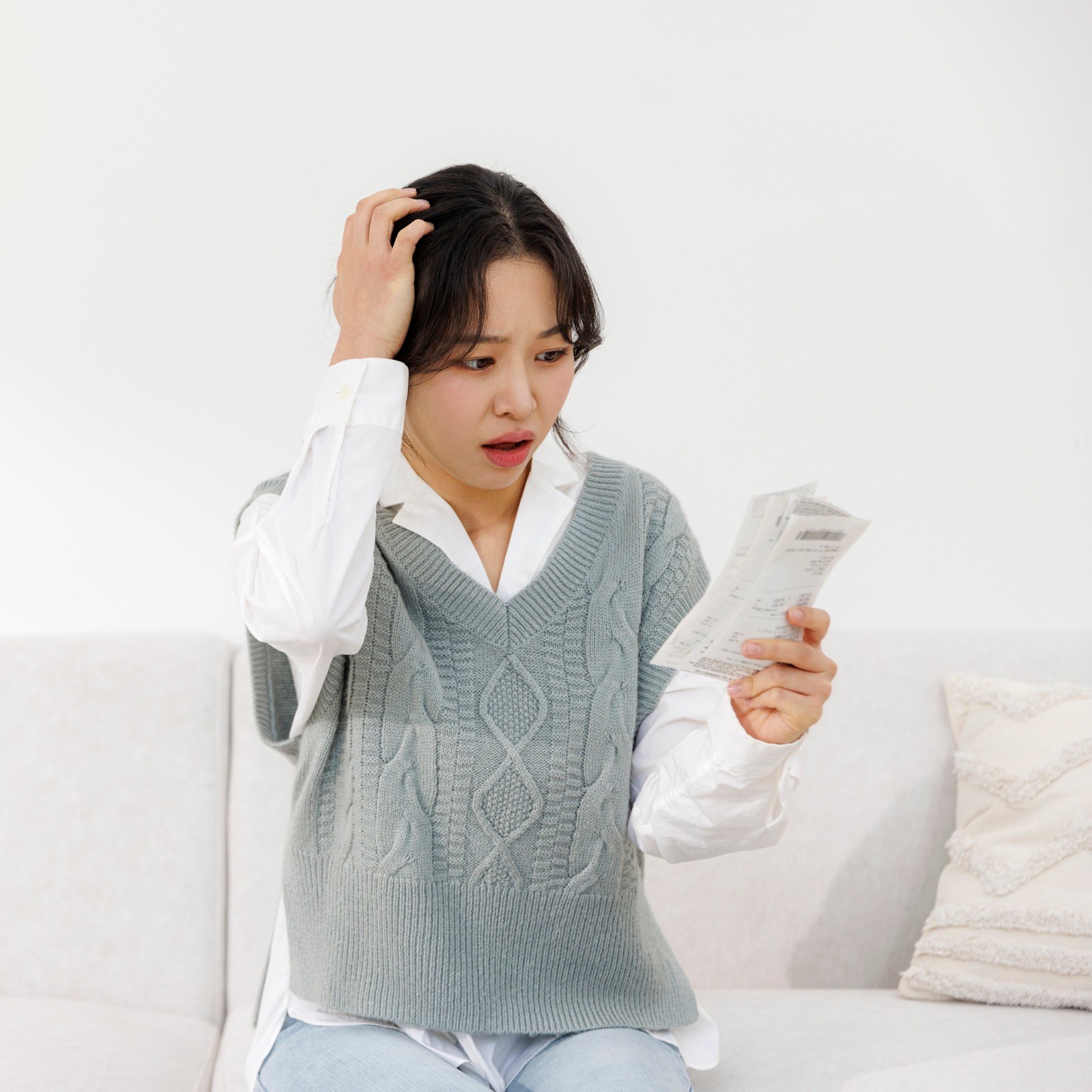 영수증 보고 머리 짚으며 놀란 여성 모습