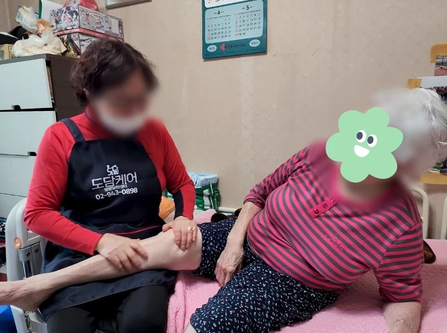 보호자에게 다리 마사지 받는 어르신 모습