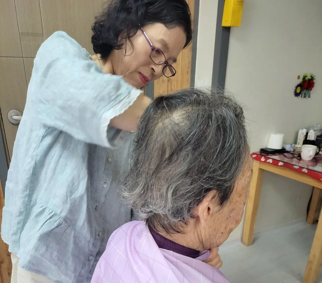 직원이 어르신의 머리를 손질해 주는 모습