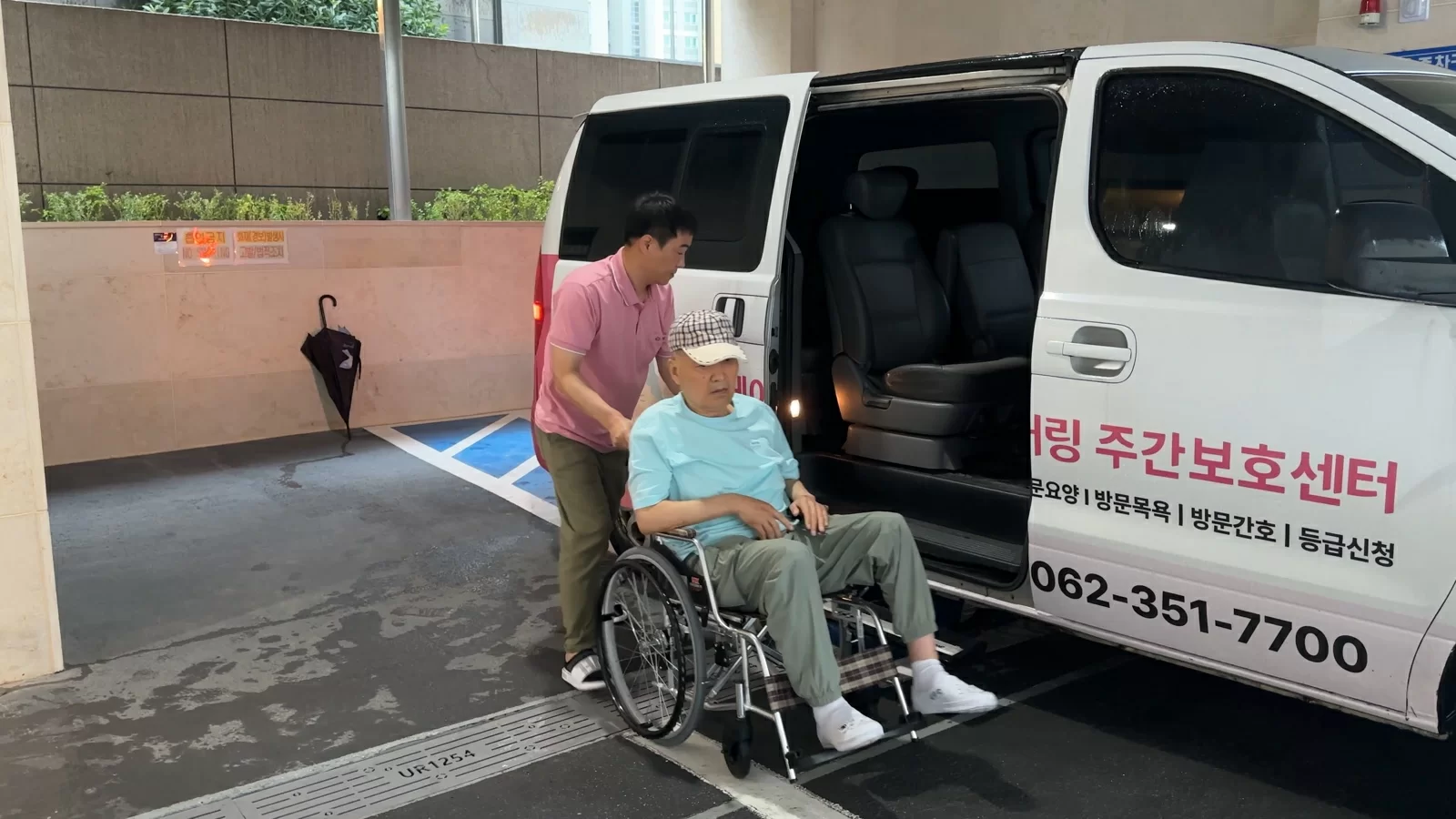 직원이 휠체어 어르신의 송영 차량 탑승을 돕는 모습