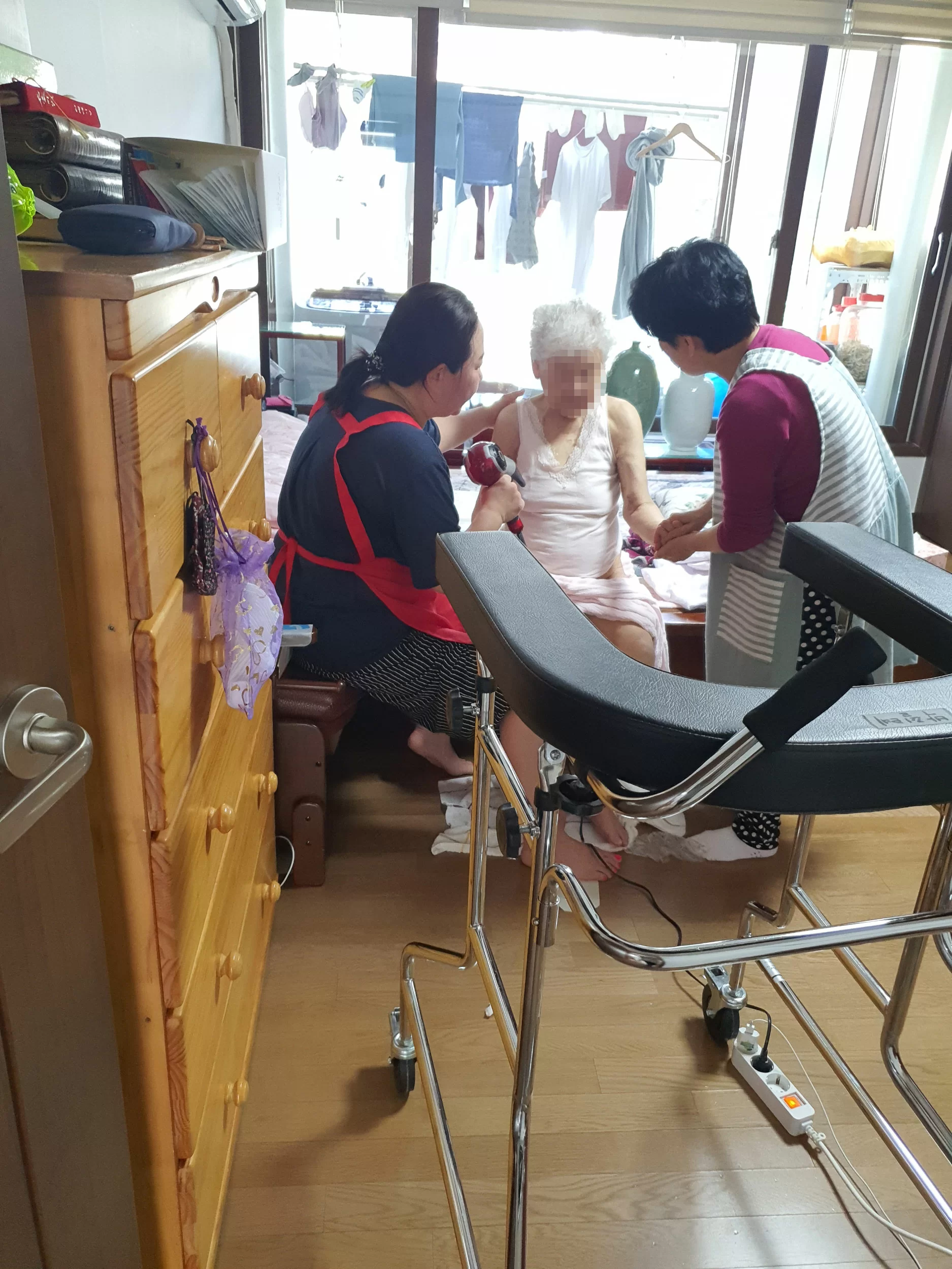 가정에서 요양보호사 2인이 어르신을 돌보는 모습
