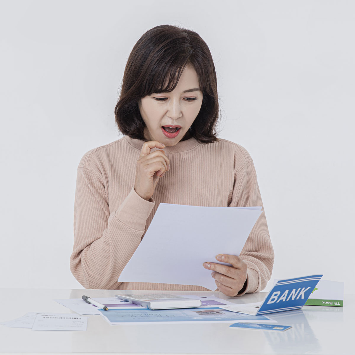 은행 서류를 보며 놀란 표정을 짓는 여성