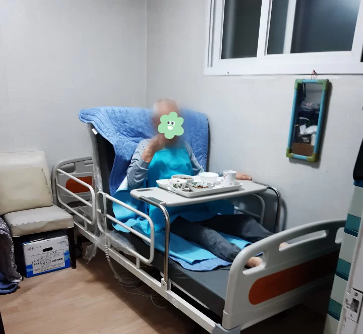 어르신이 집 안 요양 침대에 누워 있는 모습