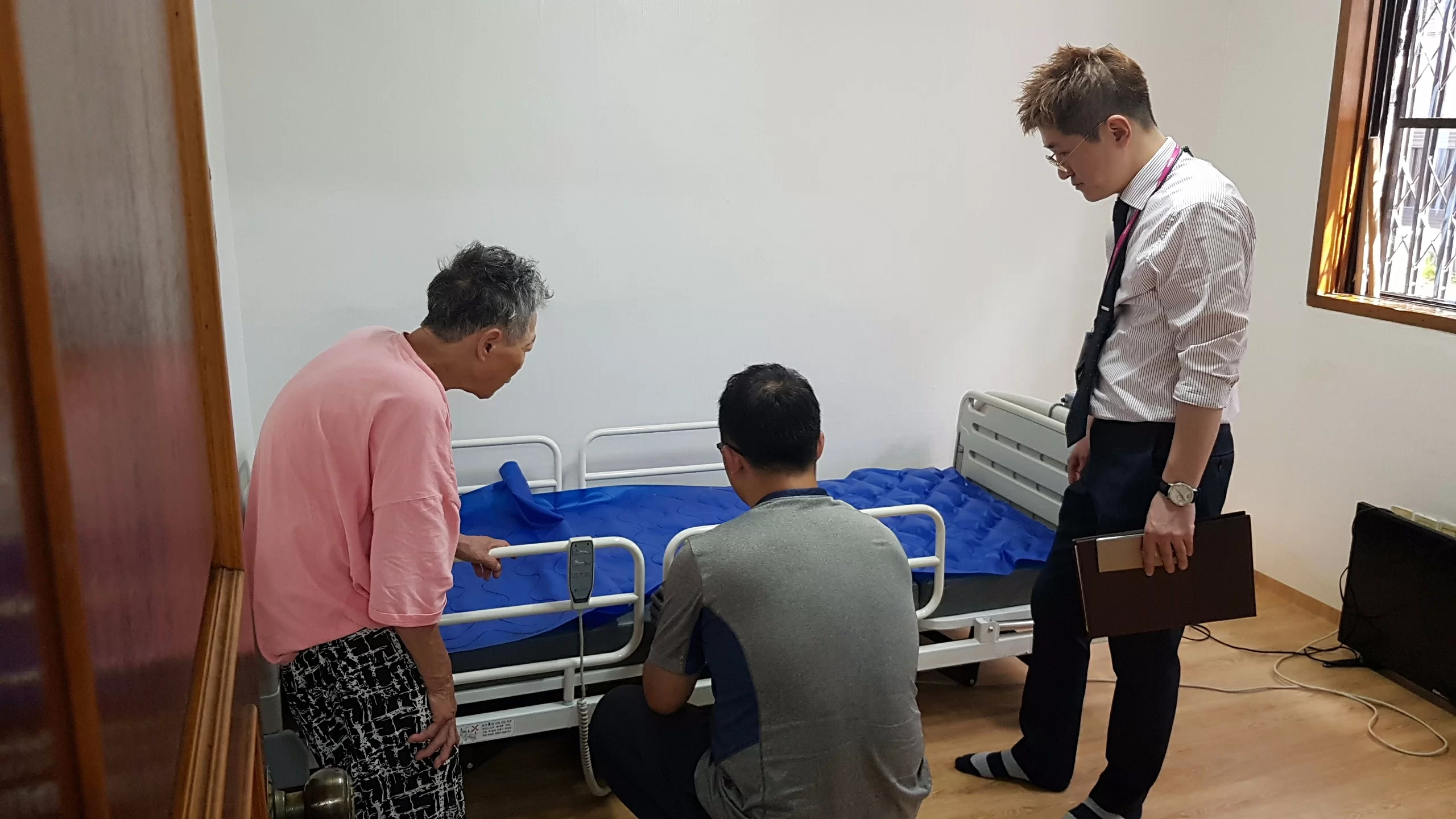 어르신과 기사가 전동침대 설치를 확인하는 모습