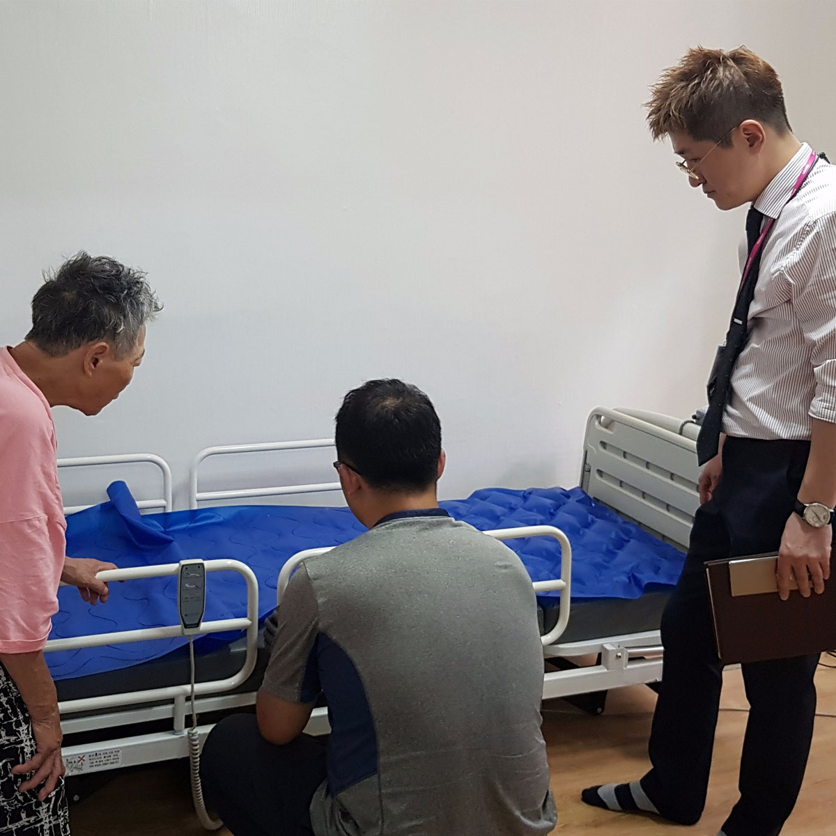 어르신과 기사가 전동침대 매트리스를 살펴보는 모습