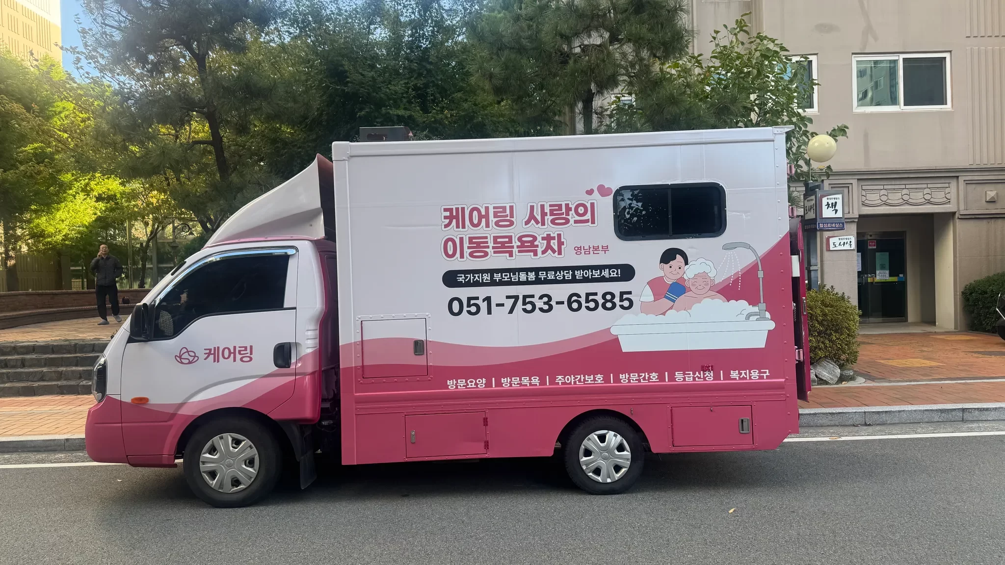 도로변에 주차된 분홍색 이동목욕차량 모습