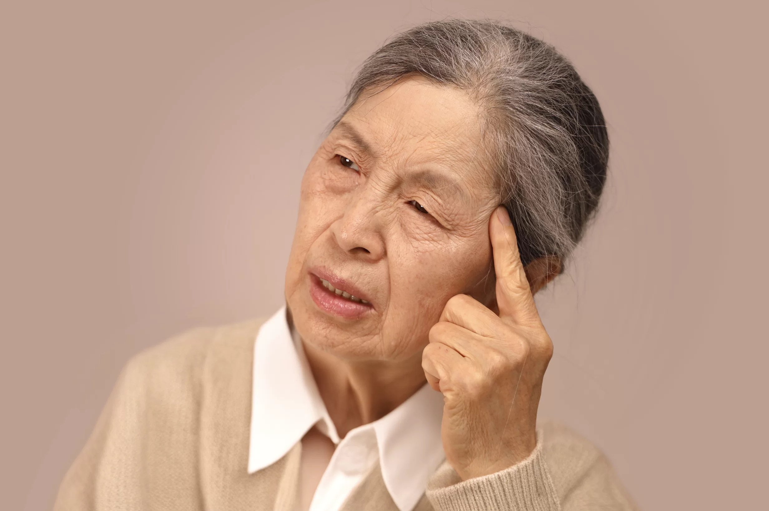 어르신이 관자놀이를 짚으며 생각하는 모습