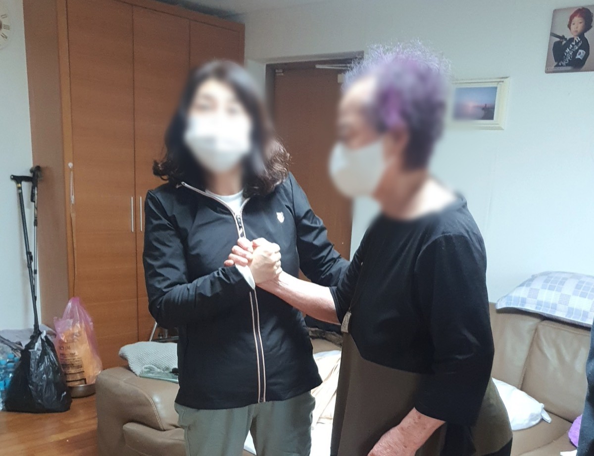 보호자와 어르신이 손을 맞잡고 선 모습