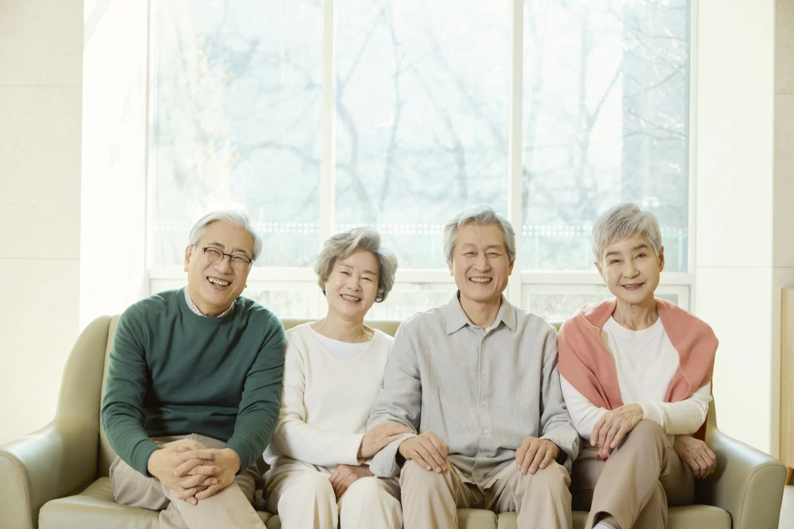 어르신 네 분이 소파에 나란히 앉아 웃는 모습