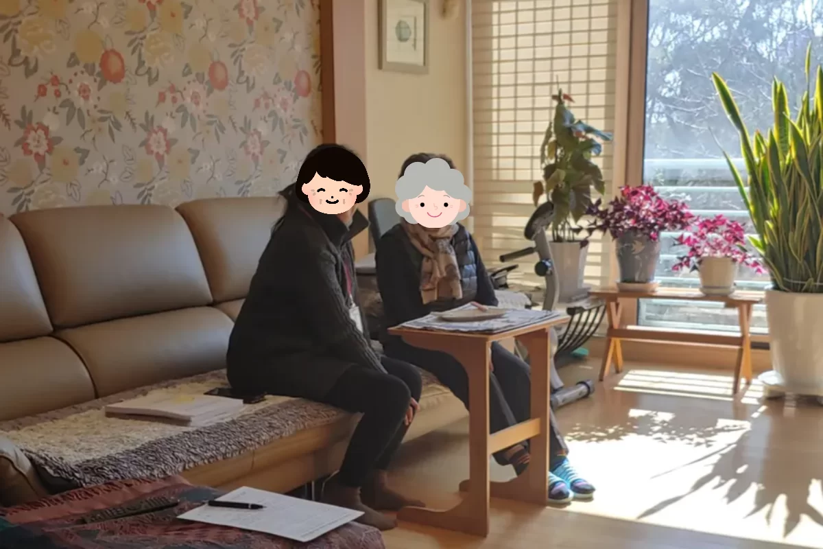 요양보호사와 어르신이 거실 소파에 함께 앉은 모습