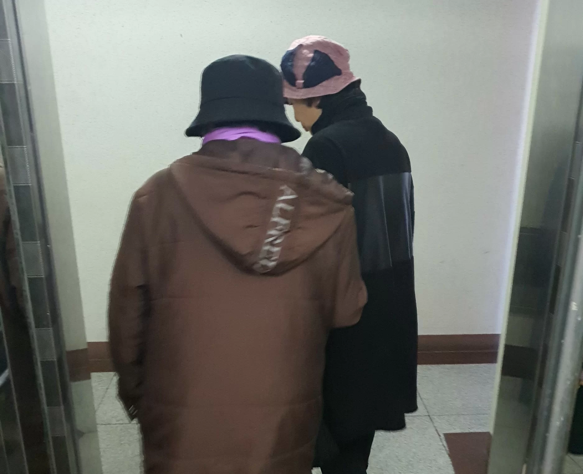 어르신과 요양보호사가 복도를 함께 걷는 뒷모습