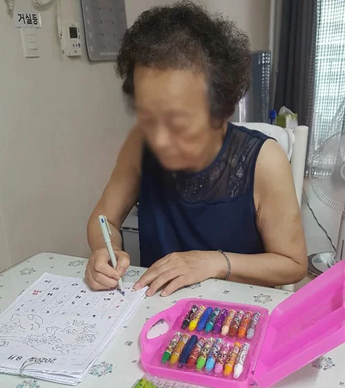 어르신이 식탁에서 글씨 쓰기를 연습하는 모습
