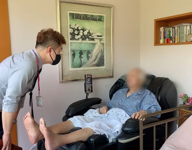 침대에 누운 어르신을 종사자가 살피는 모습