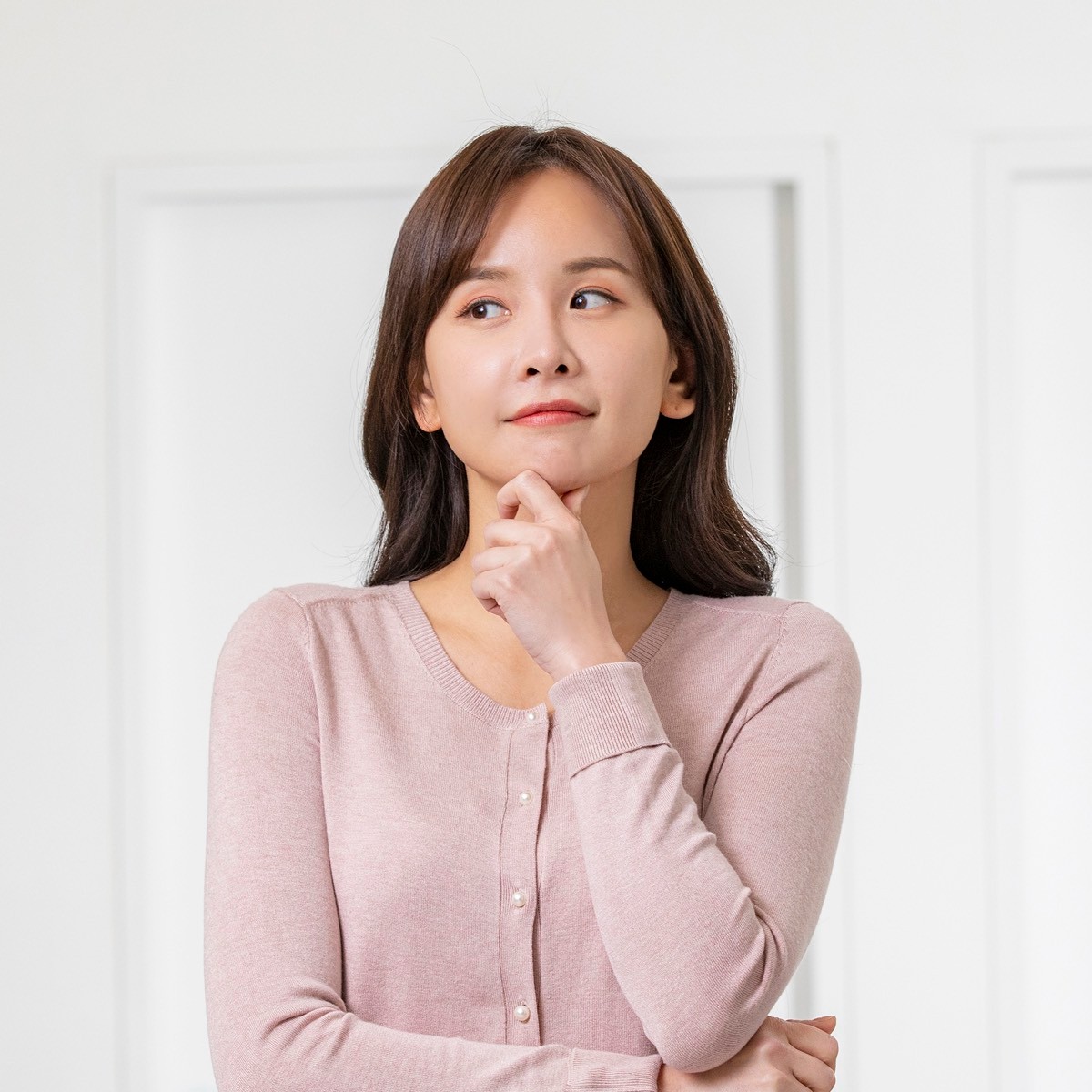 한 여성이 턱에 손을 얹고 고민하는 모습