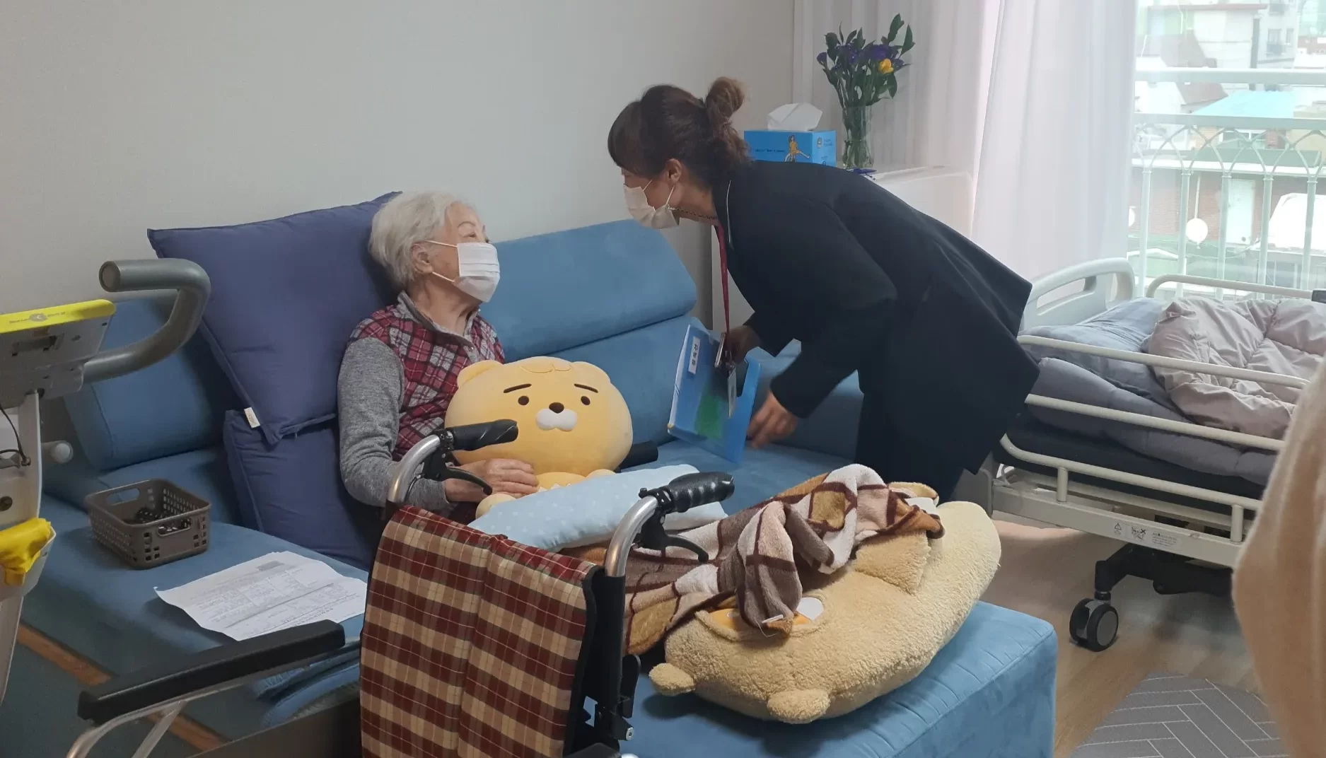 요양보호사가 침대에 앉은 어르신을 방문한 모습