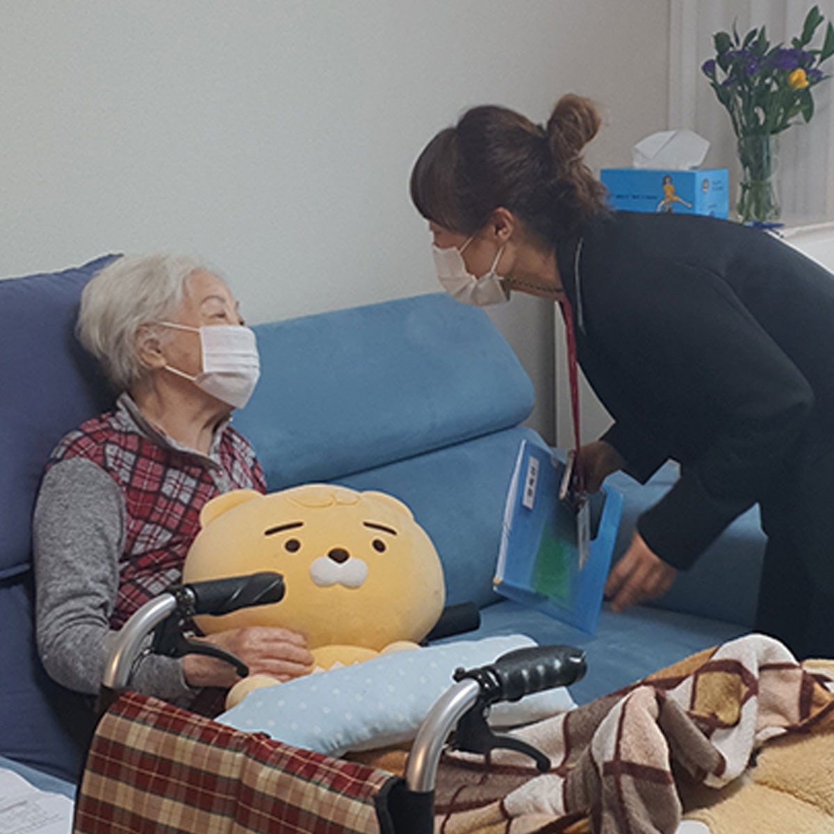 요양보호사가 침대에 앉은 어르신과 마주한 모습