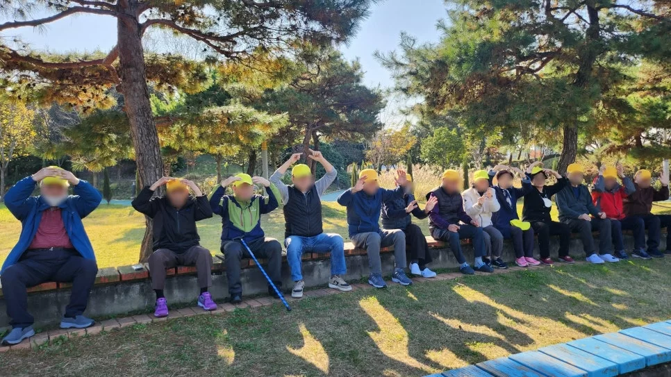 어르신들이 공원 벤치에서 하트 포즈를 하는 단체사진
