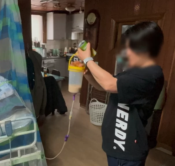요양보호사가 비위관 영양액 주머니를 관리하는 모습