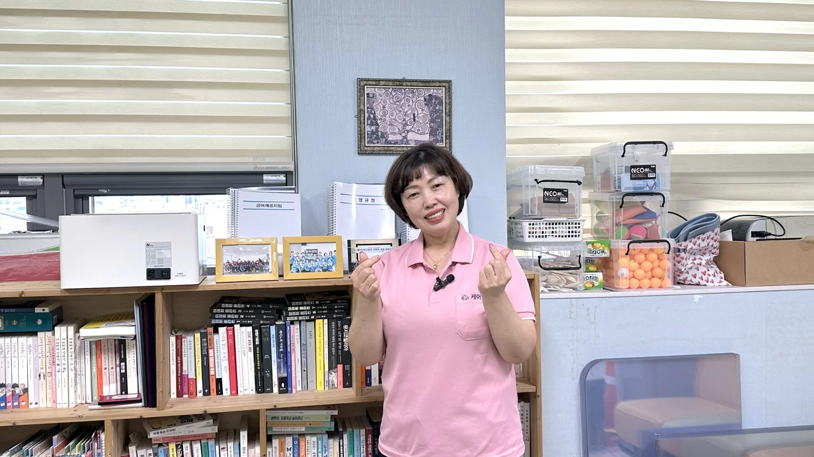 요양보호사가 센터에서 손하트를 하며 선 모습