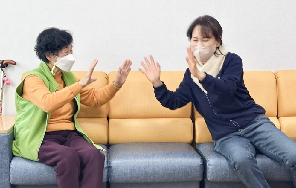 주간보호센터에서 어르신과 손뼉치며 활동하는 모습