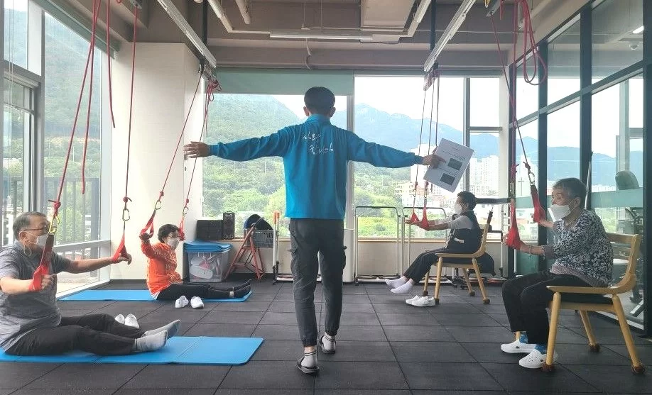 주간보호센터에서 어르신들이 슬링 운동하는 모습