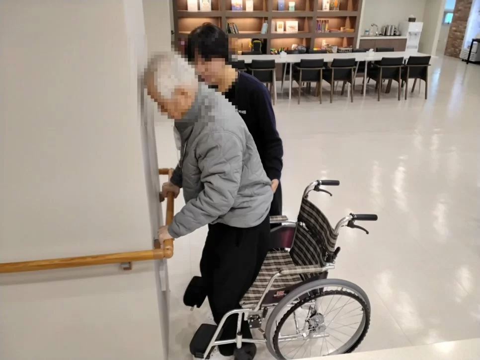 주간보호센터 직원이 어르신 보행 재활을 돕는 모습