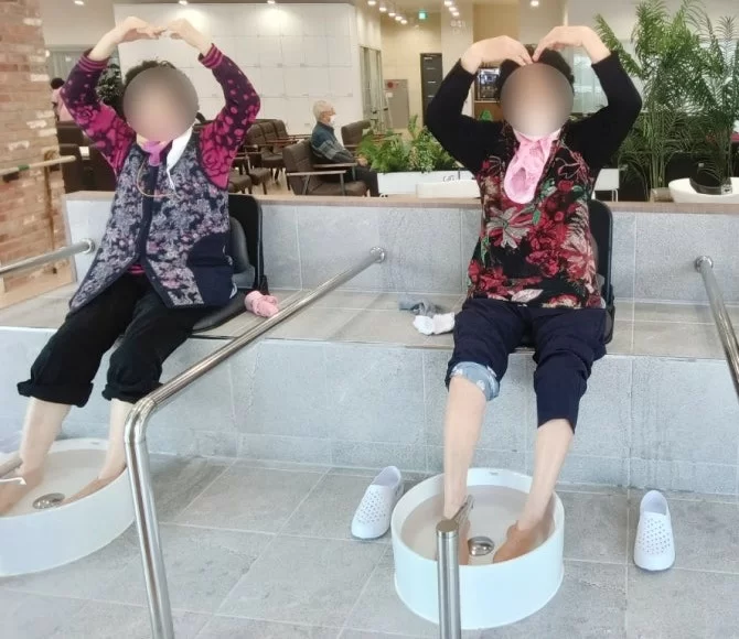 주간보호센터에서 어르신들이 족욕하며 손하트를 하는 모습