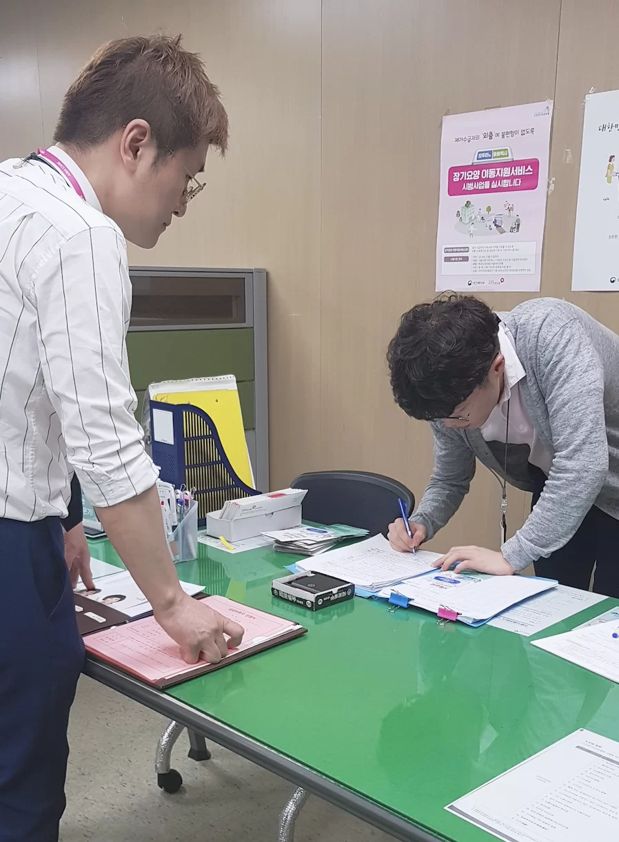 케어링 직원과 보호자가 등급 신청 서류를 작성하는 모습