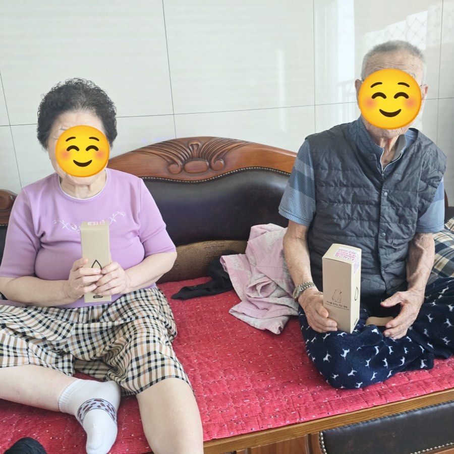 어르신 두 분이 선물을 들고 함께 앉은 모습