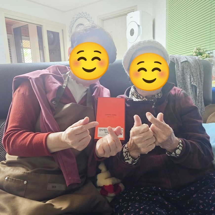 어르신 두 분이 함께 사진을 들고 앉은 모습
