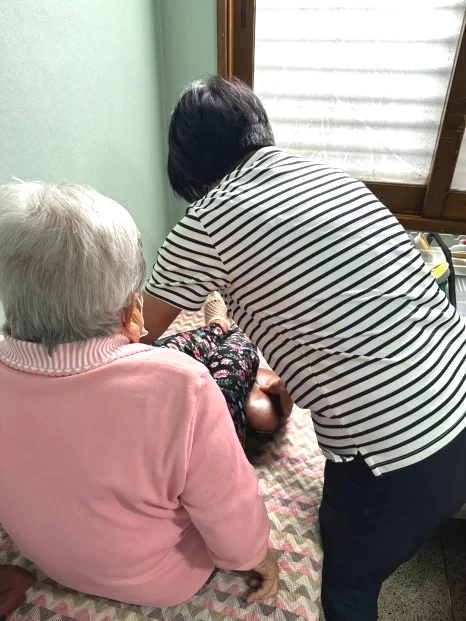 요양보호사가 어르신 발을 살피며 돕는 모습